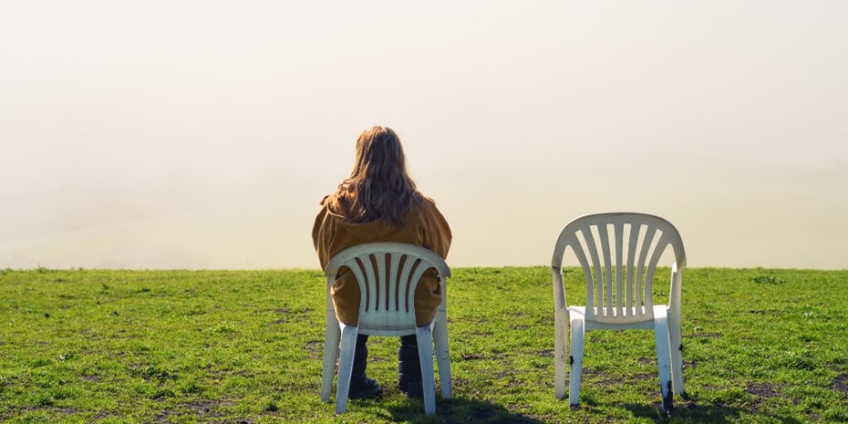 Woman sitting on white garden chair on green grass