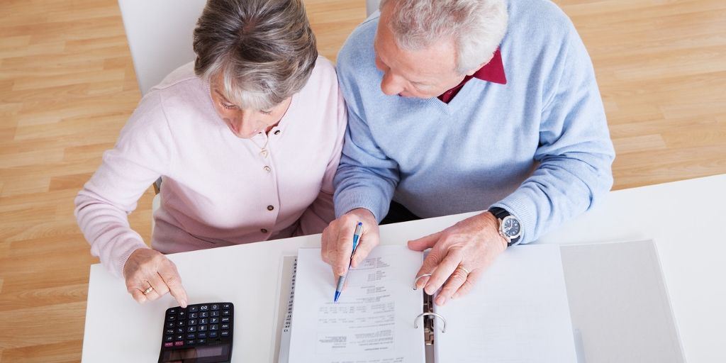 Two people sitting at table completing paperwork.