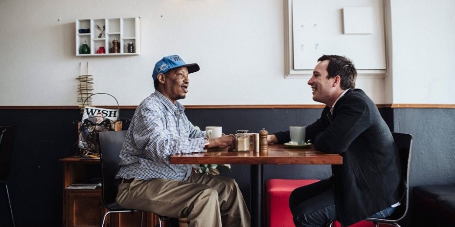 Support worker with client having a coffee and smiling