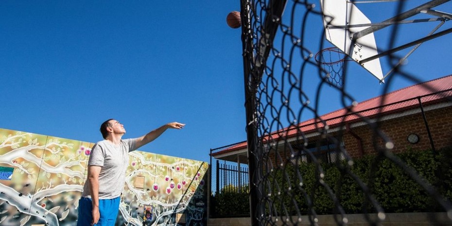 Man wearing grey shirt and blue shorts shooting a basketball