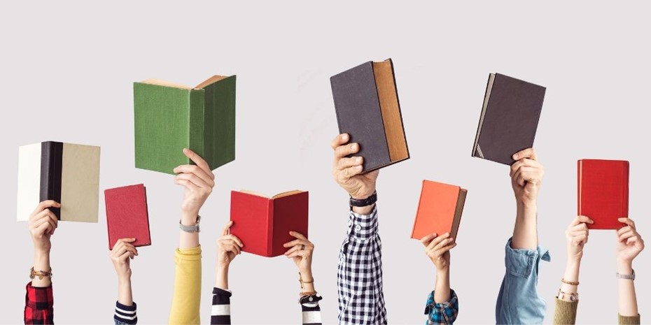 Hands outstretched holding books of multiple colours