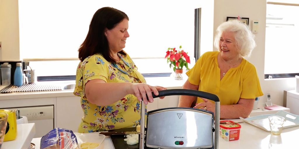 Two people using a kitchen appliance.