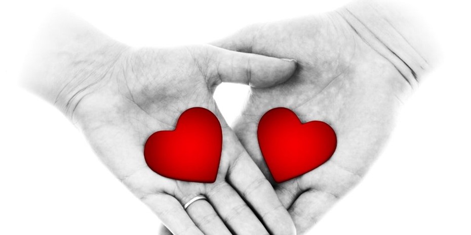 Black and white close up of a woman's and a man's hand with love hearts