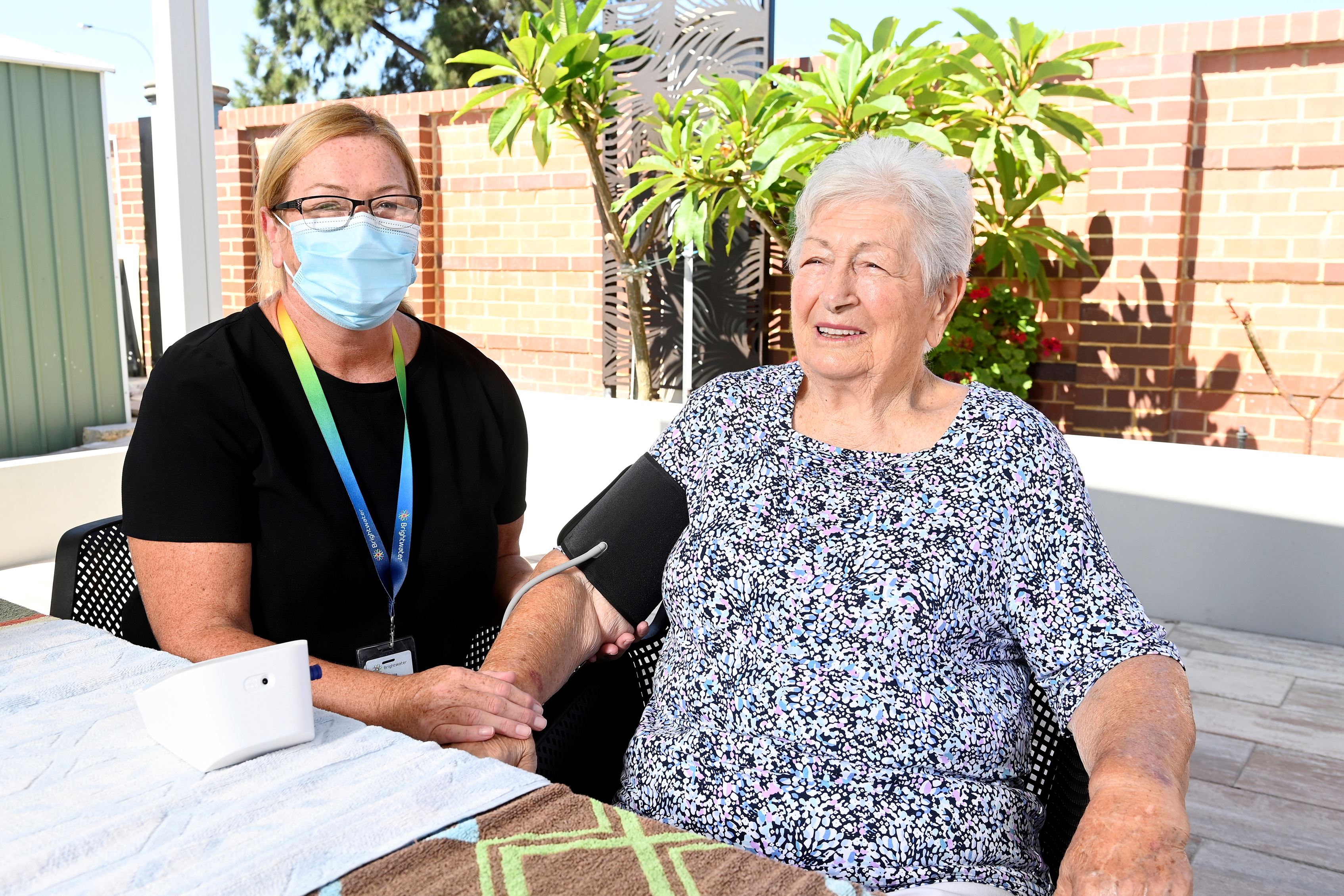 Nurse sitting with a client, taking their blood pressure.