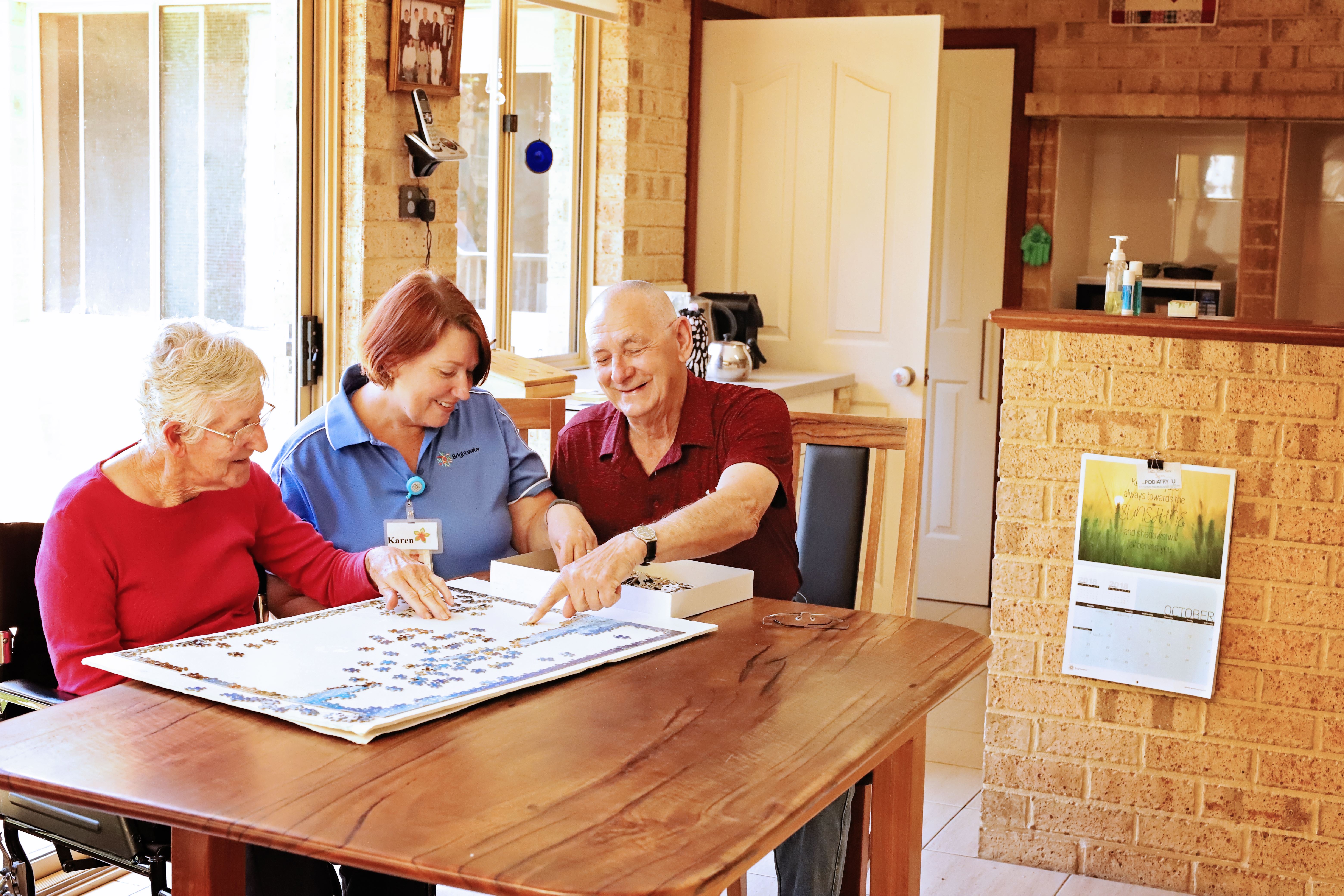 People sitting at table completing puzzle.